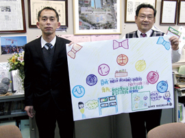 A4用紙をA0サイズに拡大出力した児童の作品を手に。新村 出 校長（右）と奥山 圭一 副校長（左）。